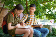 © soleg - students a boy and a girl are sitting on a bench outside the school building, they are reading books and talking
