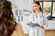 © Syda Productions - medicine, healthcare and people concept - female doctor with clipboard talking to smiling woman patient at hospital