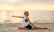 Leinwandbild Motiv fitness, sport, and healthy lifestyle concept - woman doing yoga pigeon pose on beach over sunset