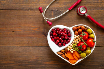Wall Mural - Healthy food in heart shaped plate with stethoscope. Healthy nutrition eating
