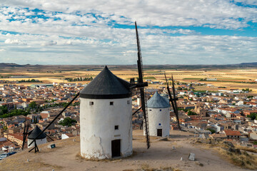 Wall Mural - Beautiful wind mill isolated in top of a hill near to Consuegra city in Castilla-La Mancha - Spain. Cloudy day. In background the city of Consuegra. The land of Don Quixote