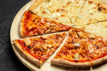 Wall Mural - Tasty hawaiian pizza with chicken and pineapple pizza Four Cheeses on wooden cutting board on a dark background. food delivery, place for text, top view