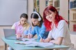 © Valerii Honcharuk - Smiling teenage female student looking at camera while sitting at desk in library