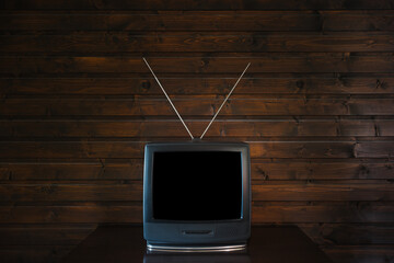 Old analoque retro tv with isolate black screen mock up on dark brown wooden background in room on table. 90's style