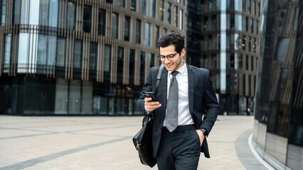 Wall Mural - The manager is a man in a business suit going to work in the office, using an app on his phone