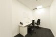 Small office cubicle with white desk and twin black chairs