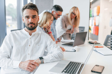 Young stylish man is working. Group of professional business people is in the office