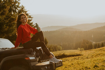 Wall Mural - Young woman relaxing on a terrain vehicle hood at countryside