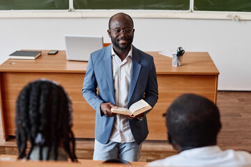 african professor reading lecture at university for students while standing in auditorium