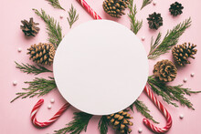 Flat Lay Christmas Composition. Round Paper Blank, Pine Tree Branches, Christmas Decorations On Colored Background. Top View, Copy Space For Text