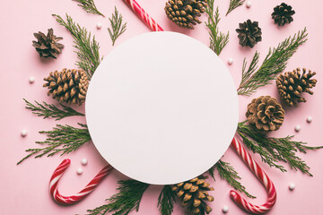 Flat lay Christmas composition. Round Paper blank, pine tree branches, christmas decorations on Colored background. Top view, copy space for text