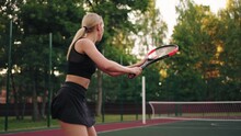 Sexy Blonde Lady In Short Black Skirt Is Playing Tennis On Outdoor Court, Rear View, Slow Motion Shot