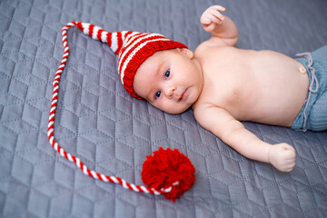 Wall Mural - Cute adorable baby lying in funny red hat. Little newborn boy with knitted hat.