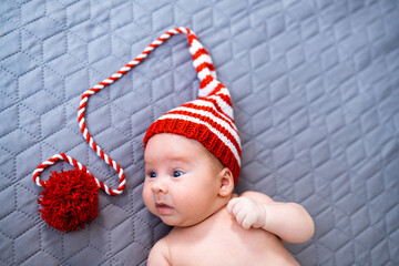 Wall Mural - Little newborn boy with knitted hat. Cute adorable baby lying in funny red hat.