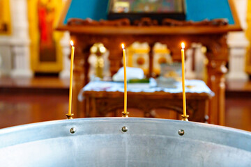 Wall Mural - burning candles on the font for baptism in the Orthodox Church.