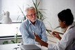 © lordn - Doctor specialist consulting a patient in a doctor's office at a clinic. Female doctor is talking with a male elderly patient.
