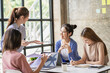 © ArLawKa - Young creative team colleague Four women discuss ideas in the boardroom. Group of Asian women during the initiation of a brainstorming session to start an office business.