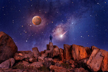 Silhouette Of A Person On Old Desert Rocks At Night With Stars And Milky Way In The Background