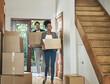 Interracial couple moving into a new modern house, carrying boxes and arriving home together. Happy, excited and smiling husband and wife walking, entering and relocating after buying an apartment