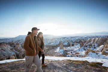 romantic asian couple enjoy their trip to cappadocia looking at the beautiful snowy landscape from the top