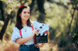 Happy Actress Holding a Cinema Clapper in the Forest. Cheerful movie protagonist starring in adaptation of a modern fairytale
