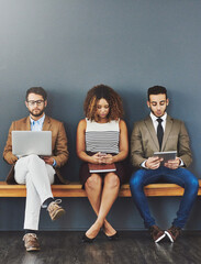 Poster - Group of design interns on wireless online devices waiting at a job interview of a startup company. Diverse people sitting, waiting for a meeting with human resources for a job