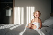 © galaganov - child in a hotel with a smile and an emotion of happiness sits on a bed in a towel with morning rays of light. Vacation
