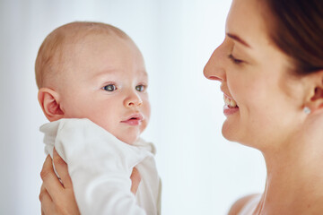 Wall Mural - A happy young mother hugging her cute baby boy at home and bonding while enjoying parenthood. Single parent being playful and affectionate, embracing precious moments with her newborn little child