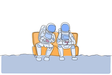 Poster - One single line drawing two young happy astronauts siting on sofa and playing video game in moon surface vector graphic illustration. Cosmonaut outer space concept. Modern continuous line draw design