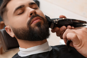 Poster - Professional hairdresser working with client in barbershop, closeup