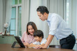 © visoot - Little boy taking online class with parents helping him at home,Boy is writing in his book.
