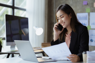 Beautiful Asian woman executives, business executives, marketing executives are talking on the phone with customers to contact the company for marketing. Marketing management concept.