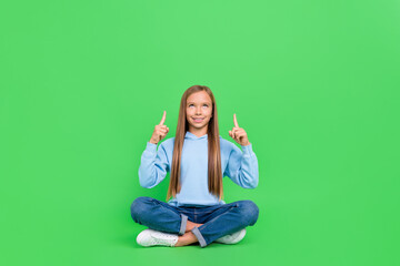 Sticker - Full size photo of small schoolgirl sit floor point look copyspace promo wear stylish blue sportswear isolated on green color background