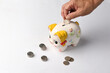Saving money in a piggy bank during recession to fight against inflation, with a white background