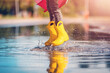© candy1812 - Child jumping in the puddle in yellow rubber boots