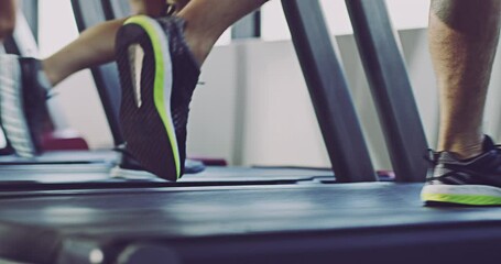 Canvas Print - People running on a treadmill equipment together as a group at indoor fitness gym showing their jogging shoes, legs and feet. Close up of fit, active and healthy men and women training doing cardio