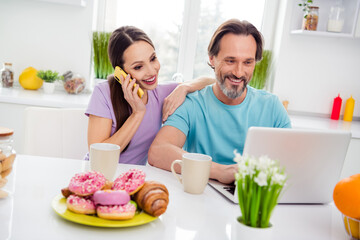 Wall Mural - Photo of excited pretty age boyfriend girlfriend wear t-shirts talking modern gadgets enjoying breakfast indoors room home