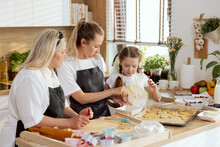 Older Sister Teaching Smaller One Whisking Eggs In Bowl For Oiling Cookies. Small Adorable Girl Trying To Do That. Elderly Mother Managing Process. Women Having Fun Together In Beautiful Tidy Kitchen