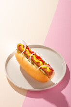 Hot dog in a round plate on white and pink background