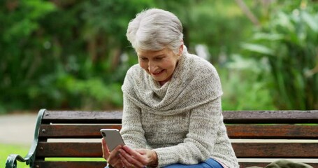 Sticker - Selfie, relaxed and senior woman holding a phone while sitting on a park bench and enjoying fresh air on a sunny day. Happy elderly lady doing video call and smiling while sitting outdoors in nature