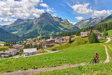 Wall Mural - active senior woman, riding her electric mountain bike above famous village of Lech in the Arlberg area , Tirol, Austrian Alps