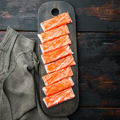 Fresh Crab meat stick surimi with blue swimming crab, on wooden cutting board, on dark wooden background, top view flat lay  , with copyspace  and space for text