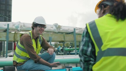 Wall Mural - Two Professional engineer man and women working checking and maintenance pipeline construction top of the building. Worker in safety uniform using tablet at pipeline construction system