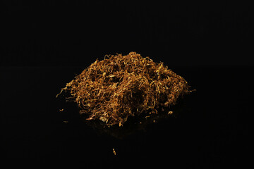 Wall Mural - Rolling tobacco on a dark table with reflection. Close-up