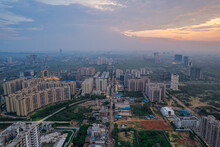 Drone Aerial Shot Showing Busy Traffic Filled Streets Between Skyscrapers Filled With Houses, Homes And Offices With A Red Sunset Sky Showing The Hustle And Bustle Of Life In Gurgaon, Delhi