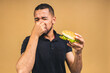 © denis_vermenko - Stop sign, bad smell. Young african american black man eating hamburger isolated over beige background. Diet concept.