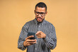 © denis_vermenko - Portrait of handsome excited thinking serious african american black guy wearing casual sending and getting messages to his lover isolated over beige background. Using phone.