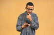 © denis_vermenko - Portrait of handsome excited thinking serious african american black guy wearing casual sending and getting messages to his lover isolated over beige background. Using phone.