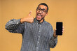 © denis_vermenko - Portrait of a smiling attractive african american black man holding blank screen mobile phone isolated over beige background.