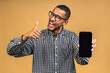 © denis_vermenko - Portrait of a smiling attractive african american black man holding blank screen mobile phone isolated over beige background.